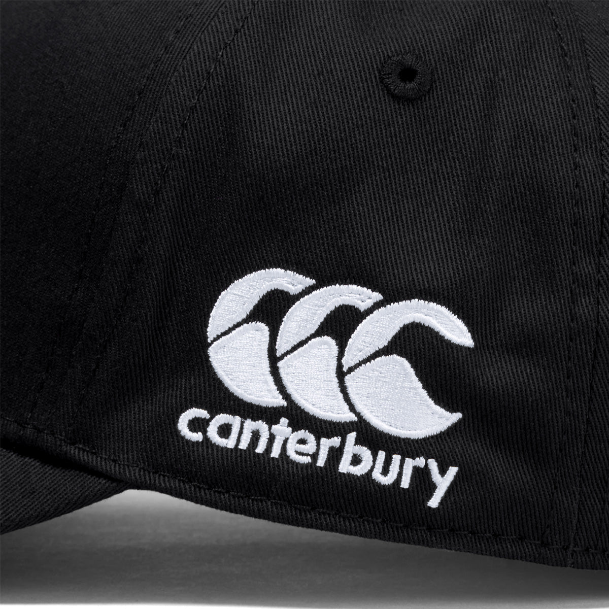 A photo of the Canterbury Team Baseball Cap in Black , close up of embroidered CCC logo.